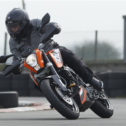 A black and orange 2011 KTM 125 Duke being ridden around a track